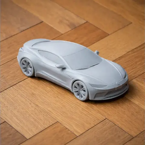 3D-printed Buick Avista model on parquet floor, showcasing sleek design and detailed wheels.