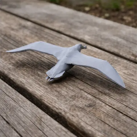 Gray 3D-printed model of an Antipodean albatross on a wooden surface, wings outstretched.