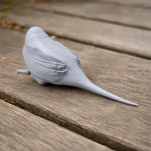 Gray 3D-printed model of a bird with a long tail, viewed from the back, on a wooden surface.