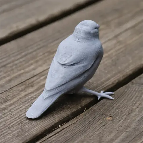 Gray 3D printed model of a bird, resembling a grosbeak, placed on wooden planks.