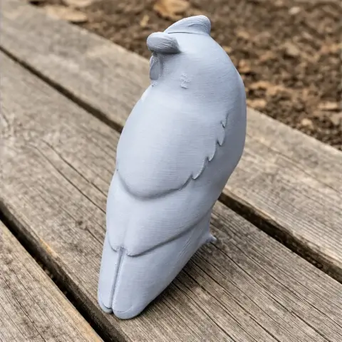 3D printed model of an Arabian scops owl, viewed from behind on a wooden surface.