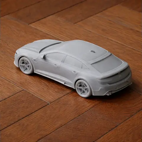 3D-printed scale model of a sleek sedan car on a wooden surface.