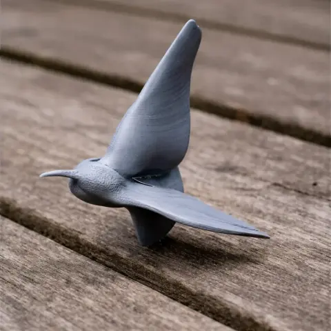 3D printed model of a prehistoric bird in flight, with detailed wings and beak on a wooden surface.