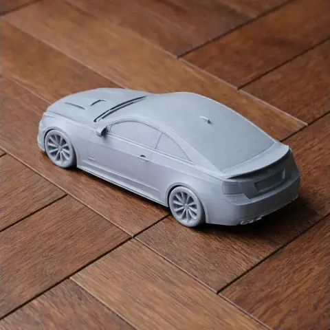 3D printed gray Cadillac ATS-V model on a wooden floor.