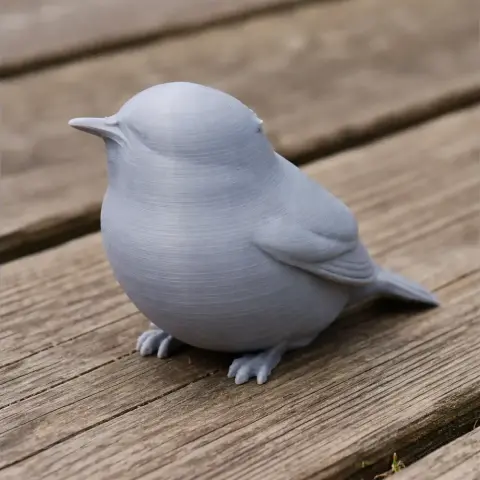 3D printed model of a bird with smooth features, sitting on a wooden surface.
