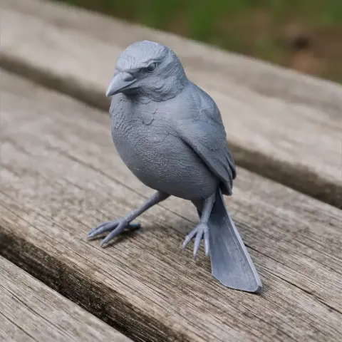 Gray 3D-printed model of a bird with detailed feathers, standing on a wooden surface.