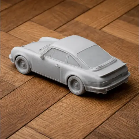 A detailed 3D-printed scale model of a classic sports car on a wooden surface.