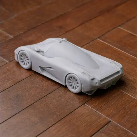 3D printed model of a sleek, futuristic sports car on a wooden surface.