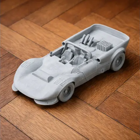 Miniature 3D-printed model of a Chaparral 2C race car on a wooden floor.