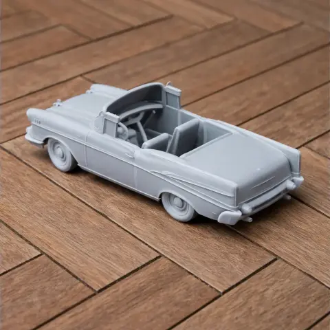 Gray 3D-printed model of a 1957 Chevrolet Bel Air car, placed on a wooden surface.
