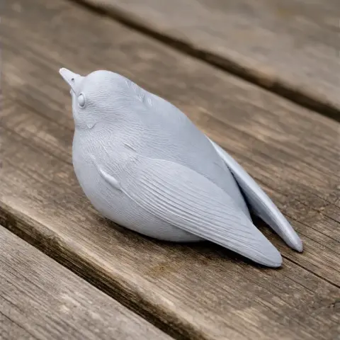 A detailed 3D printed model of a small bird, resting on a wooden surface.