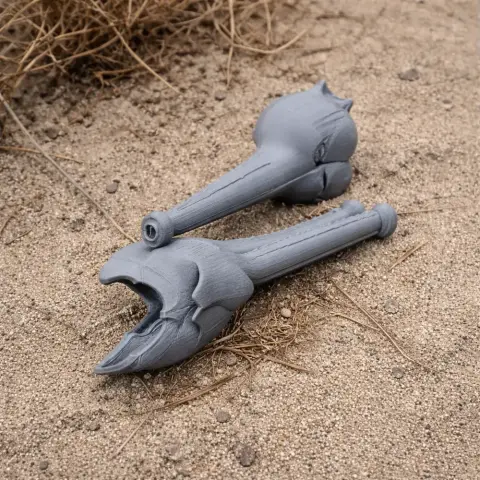 Two 3D-printed gray dinosaur skull models lie on sandy ground.