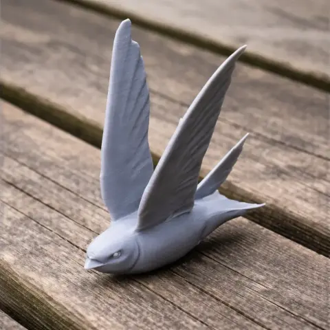 3D-printed model of a prehistoric bird with outstretched wings, displayed on a wooden surface.