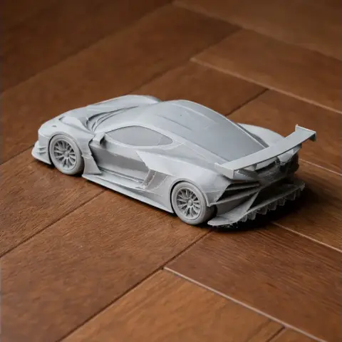 3D-printed model of a Chevrolet Corvette C8.R with detailed aerodynamic features, on a wooden surface.