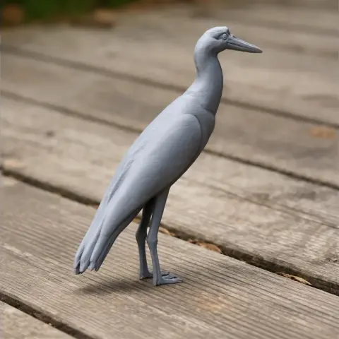 Gray 3D-printed model of an Asian woolly-necked stork on a wooden surface.
