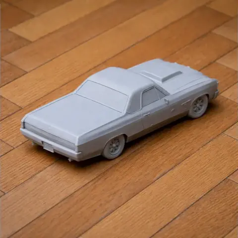 3D printed model of a Chevrolet El Camino on a wooden floor, unpainted and sitting at an angle.