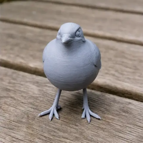 Gray 3D-printed bird model with detailed feathers, standing on wooden surface.