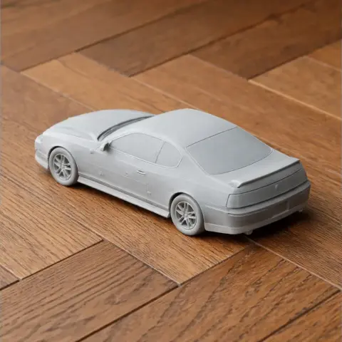 A 3D-printed model of a Chevrolet Monte Carlo, unpainted, on a wooden surface.