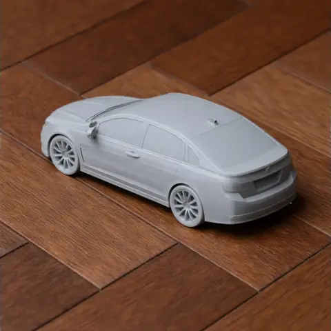 Gray 3D-printed model of a Chevrolet SS car on a wooden surface.