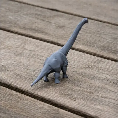 A small gray 3D-printed model of a long-necked dinosaur on a wooden surface.