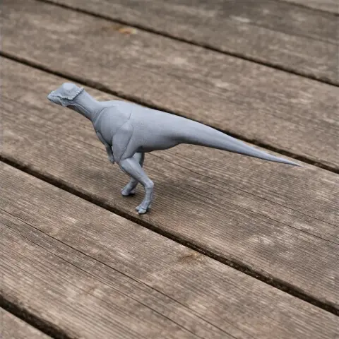 A 3D-printed model of a bipedal dinosaur with a long tail on a wooden surface.