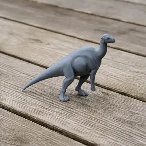 Gray 3D-printed model of a bipedal dinosaur on a wooden surface.