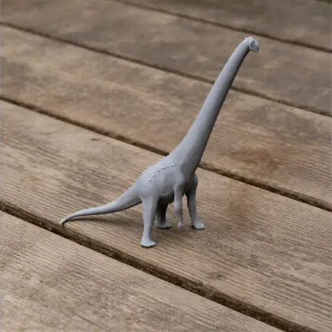Gray 3D-printed Aegyptosaurus model with long neck and tail, standing on wooden surface.