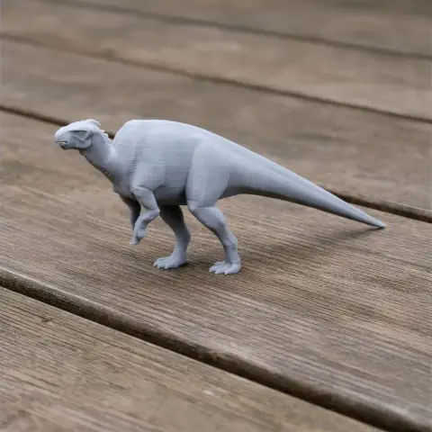 Gray 3D-printed model of a prehistoric dinosaur, standing on a wooden surface.