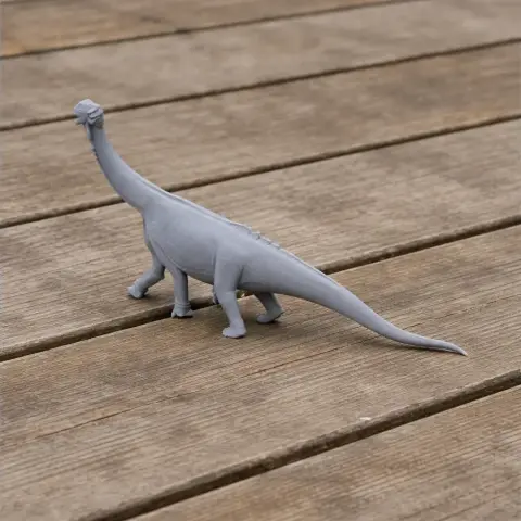 Gray 3D-printed model of a long-necked prehistoric animal on a wooden surface.