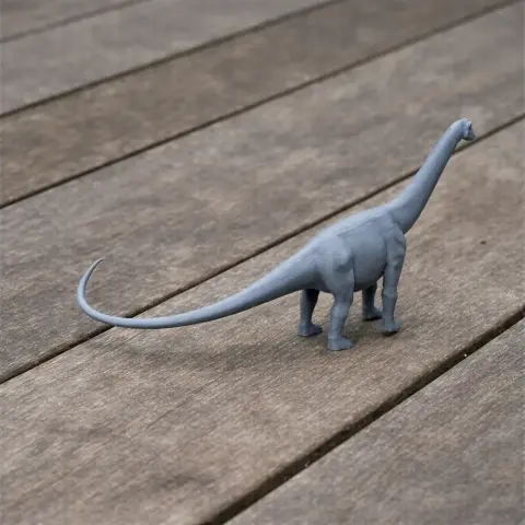 A gray 3D printed model of a long-necked, four-legged dinosaur on a wooden surface.