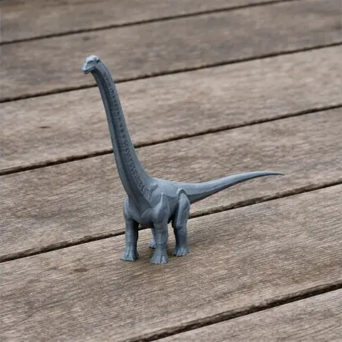 Gray 3D-printed model of a long-necked prehistoric dinosaur on a wooden surface.