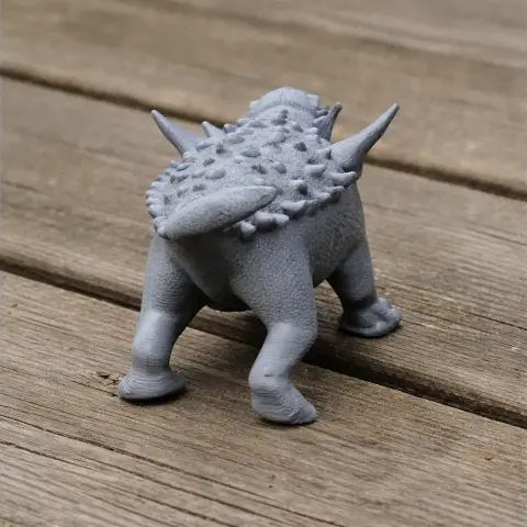 3D printed model of a spiky, four-legged prehistoric creature on a wooden surface.