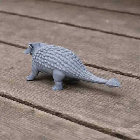 Gray 3D-printed model of an Ankylosauria with textured scales on a wooden surface.