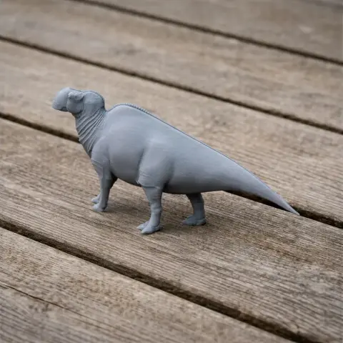 Gray 3D-printed dinosaur model with a duck-bill, standing on a wooden surface.