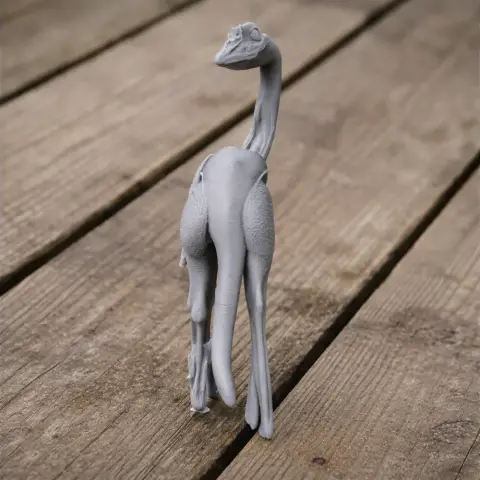 Gray 3D-printed model of a bipedal dinosaur with a long neck and tail, standing on a wooden surface.