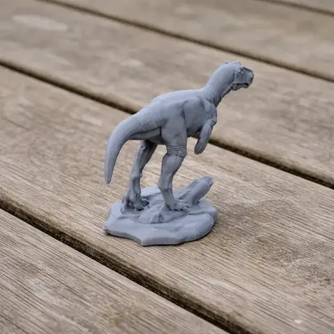Gray 3D-printed model of a prehistoric dinosaur, Asfaltovenator, standing on a textured base.