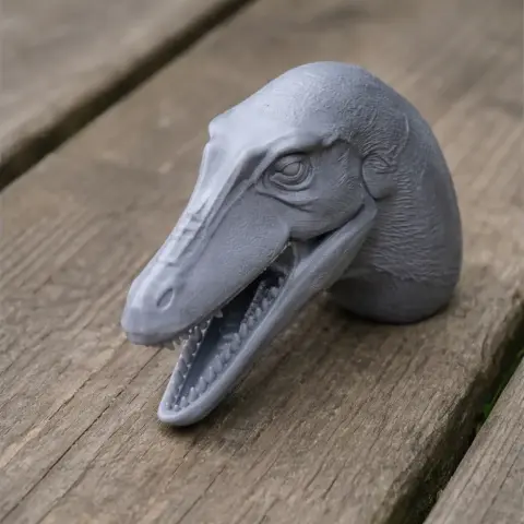 3D printed Asiatyrannus dinosaur head model, gray, with detailed features on wooden surface.