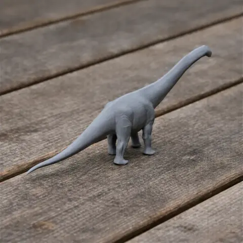 Gray 3D-printed model of a long-necked dinosaur on a wooden surface.