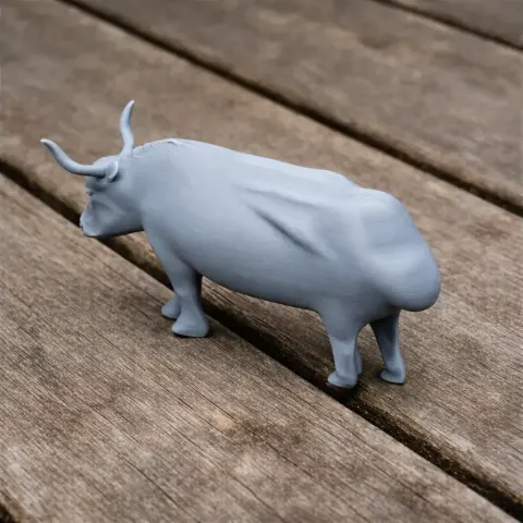 A 3D printed model of a prehistoric aurochs with prominent horns, standing on a wooden surface.