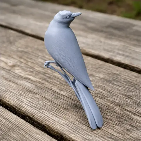 3D printed model of a bird perched on a branch, shown on a wooden surface.