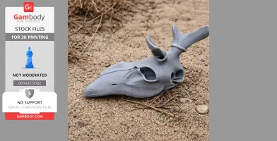 A 3D-printed gray red deer skull replica lies on sandy ground.