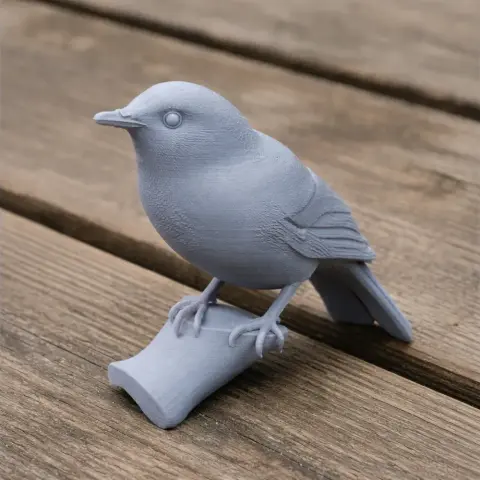 3D-printed model of a bird perched on a small branch, displayed on a wooden surface.