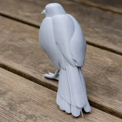 3D printed model of a bird with detailed feathers, perched on a wooden surface.