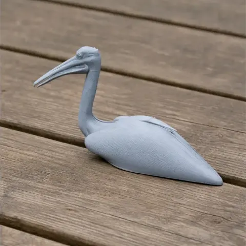 A gray 3D-printed model of an Australian pelican resting on a wooden surface.