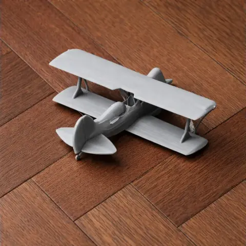 Model of a small biplane on a wooden floor, designed for 3D printing.