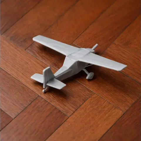 Gray 3D-printed model of a small aircraft on a wooden surface.