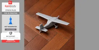 A small, gray 3D-printed model of a vintage-style aircraft on a wooden floor.