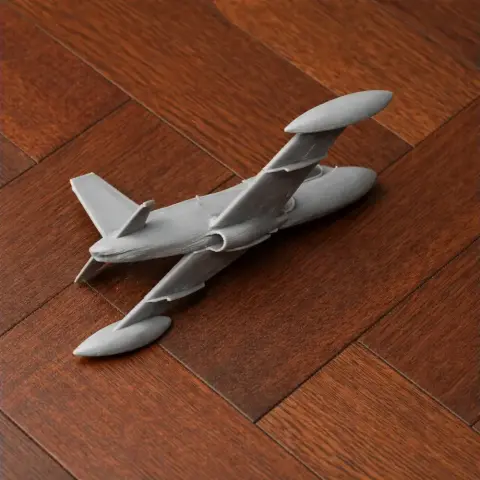 3D-printed model of Aermacchi MB-326 jet placed on a wooden surface.