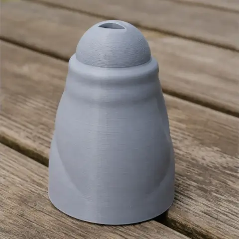 A smooth, conical 3D printed object with a small hollow on top, set on a wooden surface.