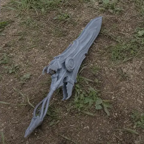 Intricately detailed large fantasy sword prop on grass and dirt.
